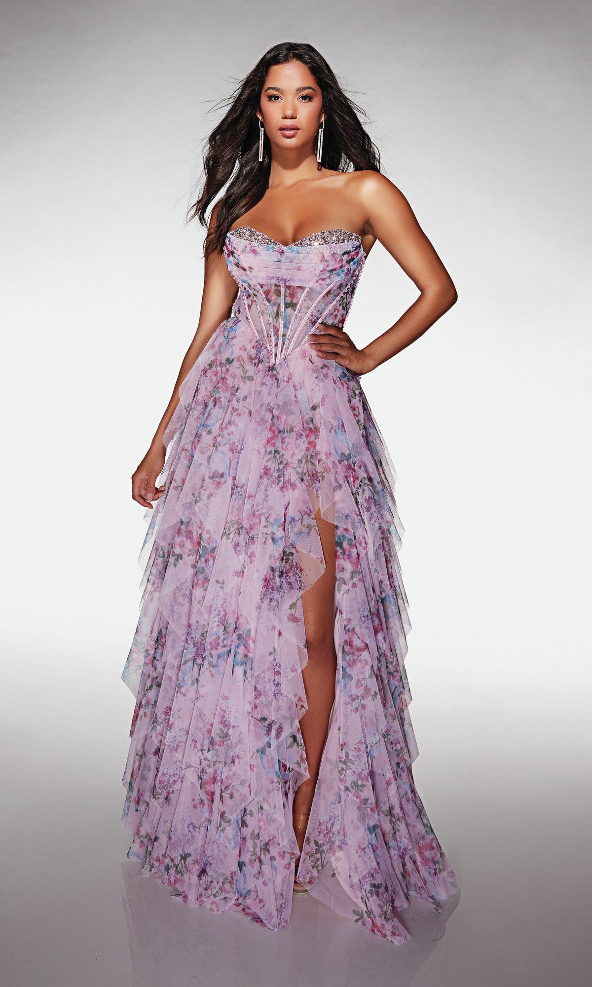 A woman models the Alyce 62041 long prom dress—a strapless, layered lilac floral gown with a sheer corset bodice and high slit—standing against a neutral backdrop.